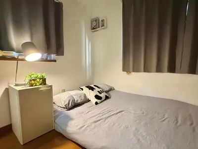 a small bedroom with a bed with a lamp and a window at Shinjuku Terasu BA in Tokyo