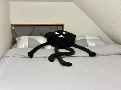 a black cat stuffed animal laying on a bed at Shinjuku Terasu BA in Tokyo