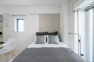 a bedroom with a bed with white walls and a window at LIVCITY Kinshicho 902 in Tokyo