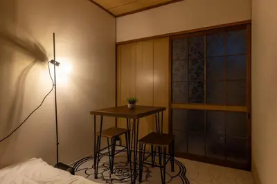 a bedroom with a table and two stools in front of a window at Ikebukuro Base in Tokyo