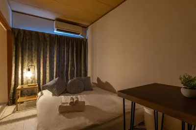 a bedroom with a bed and a table and a window at Ikebukuro Base in Tokyo