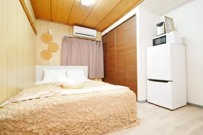 a small bedroom with a bed and a refrigerator at Ikebukuro Base in Tokyo