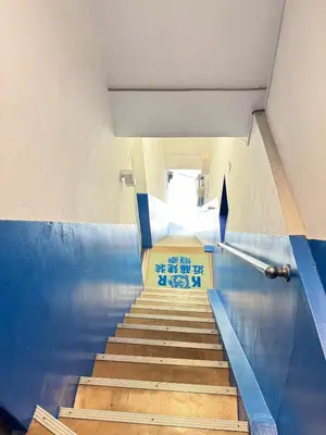 a staircase in a building with blue walls and wooden stairs at Ikebukuro Base in Tokyo