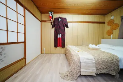 a bedroom with a bed and a suit hanging on a wall at Ikebukuro Base in Tokyo