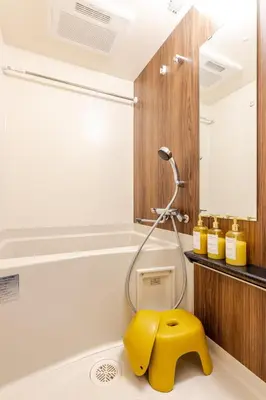 a bathroom with a yellow stool in a bath tub at jtr\u6d45\u8349\u6a4b402 in Tokyo