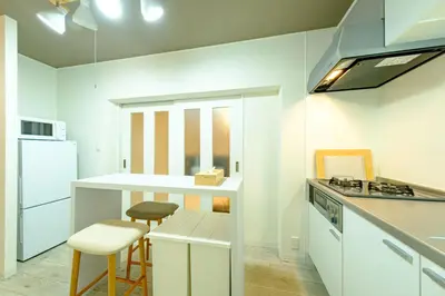 a kitchen with white cabinets and a counter with stools at \u30af\u30ec\u30a2\u30fc\u30ec\u795e\u697d\u5742\u30b2\u30b9\u30c8\u30cf\u30a6\u30b9105\u53f7\u5ba4 - \u6771\u4eac\u89b3\u5149\u306b\u4fbf\u5229 - \u725b\u8fbc\u795e\u697d\u5742\u99c5\u304b\u3089\u5f92\u6b693\u5206 in Tokyo