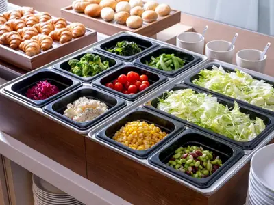 a buffet line with trays of vegetables and bread at Keio Presso Inn Akasaka in Tokyo