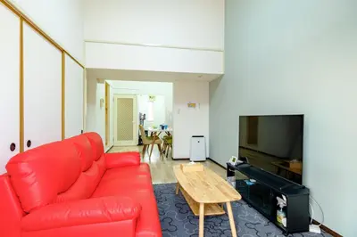 a living room with a red couch and a table at \u3055\u304f\u3089\u30cf\u30a6\u30b9 - Sakura house - \u5e83\u3005\u5feb\u9069 \u6700\u59276\u540d\u6ede\u5728\u53ef in Tokyo