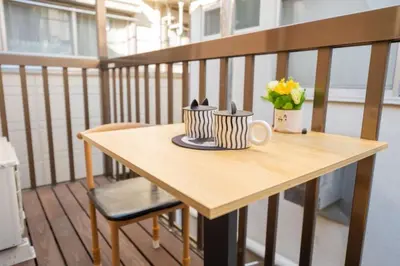 a wooden table on a balcony with a vase of flowers at \u738b201\u8d85\u5927\u9732\u53f0\u6574\u5957\u79c1\u4eba\u536b\u6d74\u53a8\u623f \u6d17\u8863\u673a \u8f66\u7ad9\u6b65\u884c5\u5206\u949f \u4e0a\u91ce\u7ad9\u5730\u94c1\u76f4\u8fbe in Tokyo