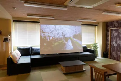 a living room with a black couch and a large screen at SLEEPLAB \u795e\u697d\u5742 -Kagurazaka- in Tokyo