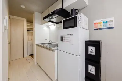 a small kitchen with a refrigerator and a sink at RECO Waseda by Tranova in Tokyo