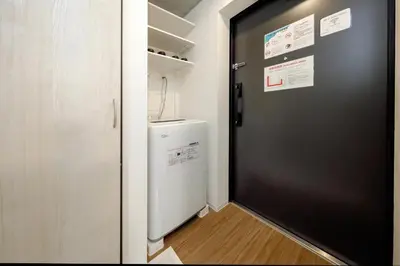 a black door leading into a laundry room with a refrigerator at RECO Waseda by Tranova in Tokyo