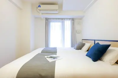 a bedroom with a large white bed with blue pillows at \u30a2\u30eb\u30ab\u30c7\u30a3\u30a2\u897f\u84b2\u7530 in Tokyo