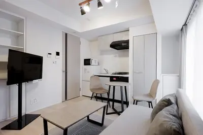 a living room with a couch and a table and a kitchen at \u30ec\u30fc\u30f4\u6d45\u8349 in Tokyo