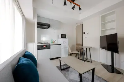 a living room with a blue couch and a kitchen at \u30ec\u30fc\u30f4\u6d45\u8349 in Tokyo