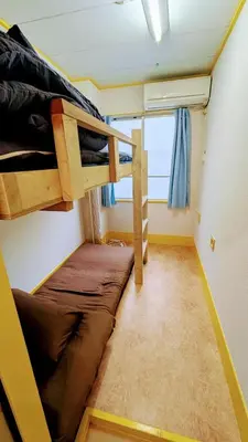 a small room with two bunk beds and a window at Joe Backpackers in Tokyo