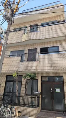 a tall brick building with black doors and windows at Joe Backpackers in Tokyo