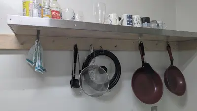 a bunch of pots and pans hanging on a wall at Joe Backpackers in Tokyo