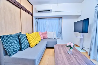 a living room with a blue couch with colorful pillows at Direct Shinjuku Max 10 Tokyo Hostel Shinozaki in Tokyo