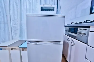 a white refrigerator in a kitchen next to a stove at Direct Shinjuku Max 10 Tokyo Hostel Shinozaki in Tokyo