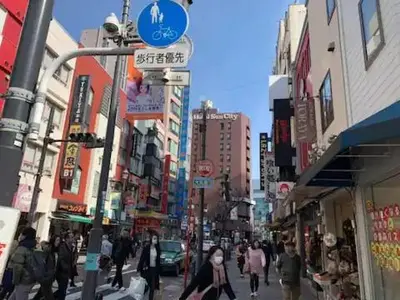 a group of people walking down a busy city street at COMMA HOUSE Nishi-Ikebukuro 102 in Tokyo