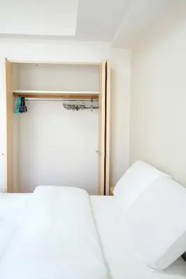 two beds in a small room with a closet at LJ Hotel Shinjuku in Tokyo