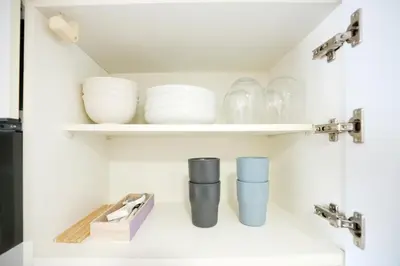 a kitchen shelf with plates and cups on it at LJ Hotel Shinjuku in Tokyo