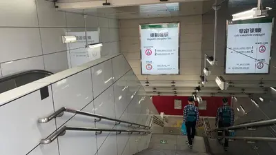 two people walking down escalators in a building at LJ Hotel Shinjuku in Tokyo