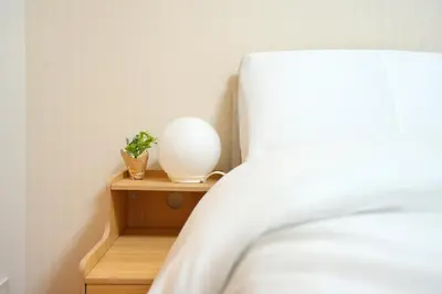 a white vase on a wooden shelf next to a bed at LJ Hotel Shinjuku in Tokyo