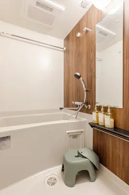 a bathroom with a green stool next to a bathtub at jtr\u6d45\u8349\u6a4b502 in Tokyo