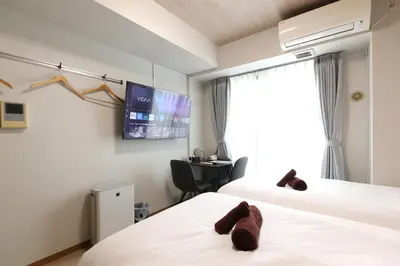 a hotel room with two beds and a tv at \u30cb\u30e5\u30fc\u30ac\u30a4\u30a2 \u30ea\u30eb\u30fc\u30e0\u829d No27 - \u6771\u4eac\u30bf\u30ef\u30fc,\u829d\u516c\u5712\u3082\u5f92\u6b69\u570f\u5185 - \u7fbd\u7530\u76f4\u901a - \u5c71\u624b\u7dda\u5229\u7528 in Tokyo
