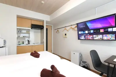 a bedroom with a bed and a tv on the wall at \u30cb\u30e5\u30fc\u30ac\u30a4\u30a2 \u30ea\u30eb\u30fc\u30e0\u829d No27 - \u6771\u4eac\u30bf\u30ef\u30fc,\u829d\u516c\u5712\u3082\u5f92\u6b69\u570f\u5185 - \u7fbd\u7530\u76f4\u901a - \u5c71\u624b\u7dda\u5229\u7528 in Tokyo