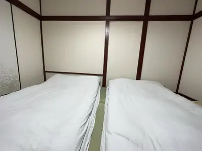 two beds in a room with white sheets at \u6d45\u8349 \u30b9\u30ab\u30a4\u30c4\u30ea\u30fc\u570f10\u5206 \u4ea4\u901a\u81f3\u4fbf \u6d45\u8349\u5bfa\u89b3\u5149\u30fc\u53cc\u9b5a\u30ce\u5bbf\u5357\u68df in Tokyo
