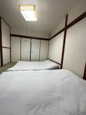a bedroom with two white beds and a light at \u6d45\u8349 \u30b9\u30ab\u30a4\u30c4\u30ea\u30fc\u570f10\u5206 \u4ea4\u901a\u81f3\u4fbf \u6d45\u8349\u5bfa\u89b3\u5149\u30fc\u53cc\u9b5a\u30ce\u5bbf\u5357\u68df in Tokyo