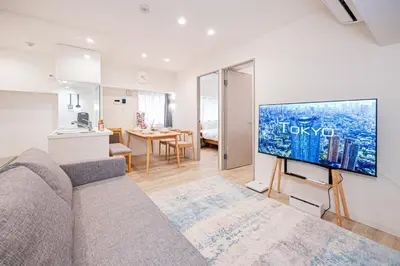 a living room with a couch and a tv on a wall at self-check in misimaya building in Tokyo