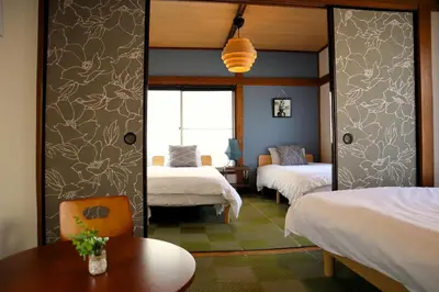 a hotel room with two beds and a table at 6 Min Walk from Aoto Station, Direct Access to Narita, Haneda Airports, Old house with modern renovation, in Tokyo