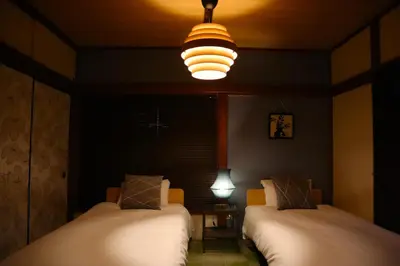 a dark room with two beds and a light at 6 Min Walk from Aoto Station, Direct Access to Narita, Haneda Airports, Old house with modern renovation, in Tokyo