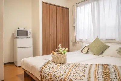 a bedroom with a bed with a microwave on top of it at shinjuku 2 stops,3-4 people,train walk for 5mins in Tokyo