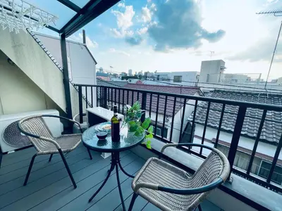 a balcony with two chairs and a table with a drink at Sakae House in Tokyo