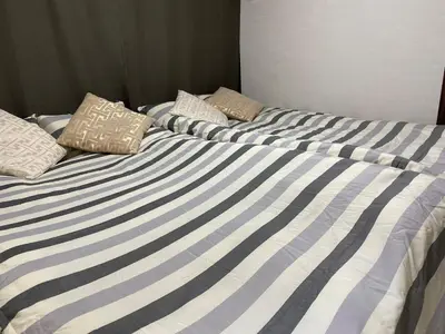 a bed with blue and white striped sheets and pillows at \u5b50\u732b\u306e\u5bb6 103t in Tokyo