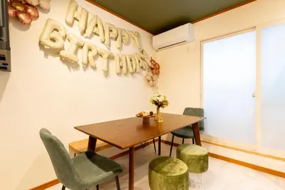 a dining room with a table and chairs and a happy birthday sign at Fantasy Lodge in Tokyo