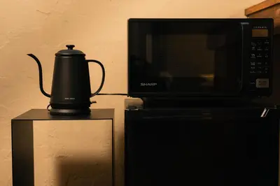 a black coffee maker sitting next to a microwave at ERA 1927 Koenji in Tokyo