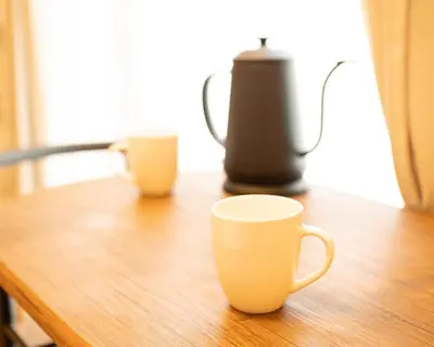 two coffee cups sitting on a wooden table at \u30b9\u30ef\u30f3\u30d1\u30fc\u30af\u6c60\u888b in Tokyo
