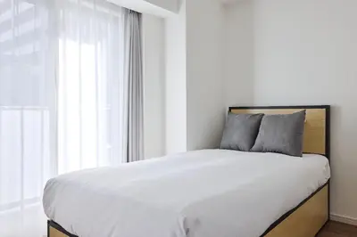 a bedroom with a bed with white sheets and a window at Miyabi \u795e\u697d\u5742 in Tokyo