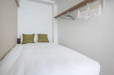 a bedroom with a white bed with green pillows at Hit\u9326\u7cf8\u753a in Tokyo