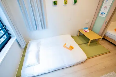 a small bedroom with a white bed and a table at Uhome Fabric Hotel in Tokyo