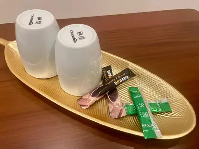a gold plate with two white cups on a table at Uhome Fabric Hotel in Tokyo