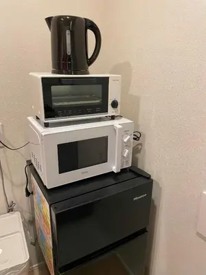 a microwave and a toaster oven on top of a refrigerator at Uhome Fabric Hotel in Tokyo