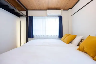 a bedroom with a large white bed with yellow pillows at \u30a2\u30ad\u30b5\u30dd\u30b9\u30c6\u30a4\u521d\u53f0 in Tokyo
