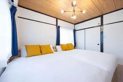a bedroom with a large white bed with yellow pillows at \u30a2\u30ad\u30b5\u30dd\u30b9\u30c6\u30a4\u521d\u53f0 in Tokyo